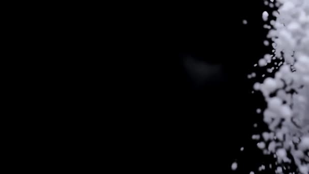 Weißer Perlzucker fällt in Zeitlupe auf schwarzem Hintergrund — Stockvideo