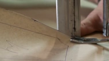 Dikiş imalatında çalışan erkek işçi elektrikli kumaş makinesi kullanıyor. Üretim hattı dikiyorum. Kumaş kesimi