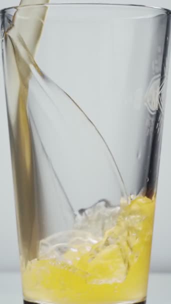 Nalévání piva do skla na bílém pozadí. Zpomalený záběr nalití zlatého ležáku do sklenice — Stock video