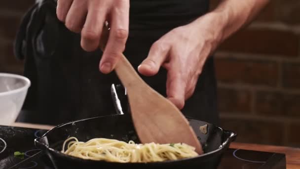 Séf tesz spagetti tészta egy serpenyőben sült gomba, fokhagyma és petrezselyem egy étterem konyhájában. Élelmiszer-összetevő. - Igen. Készítsd elő az ételt az evésre. Olasz konyha. Finom vacsora. — Stock videók