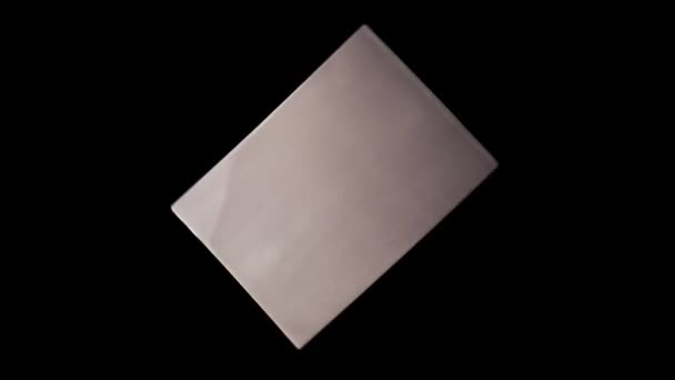 Izolovaná kovová deska s abstraktní texturou rotující na černém pozadí. Abstraktní reflexe na měděné desce — Stock video