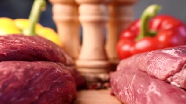 Tiro macro extremo de diapositiva entre dos filetes de carne cruda en tablero de madera con fondo colorido — Vídeo de stock