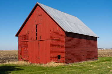 Arka planda mavi gökyüzü olan açık alanda eski kırmızı bir ahır. LaSalle County, Illinois, ABD