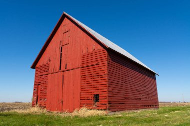 Arka planda mavi gökyüzü olan açık alanda eski kırmızı bir ahır. LaSalle County, Illinois, ABD