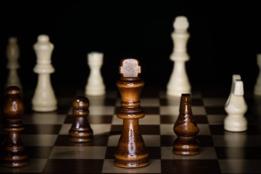 Tahta satranç tahtası ve siyah arka planı olan parçalar..