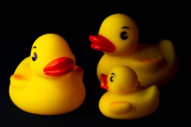 Siyah arka planı olan sarı plastik ördekler..