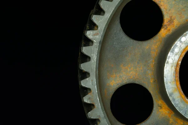 Partially rusted gear with black background.