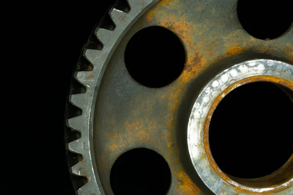 Partially rusted gear with black background.