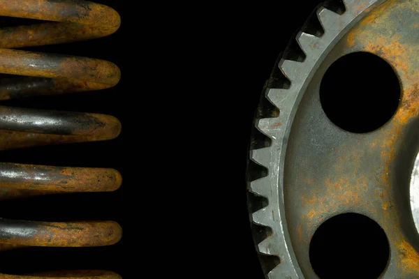 Rusted spring and gear with black background.