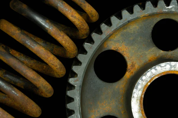 Rusted spring and gear with black background.