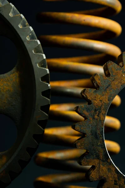 Rusted spring and gears with black background.