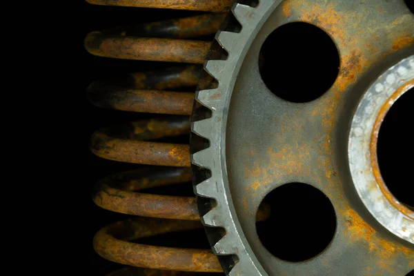 Rusted spring and gears with black background.