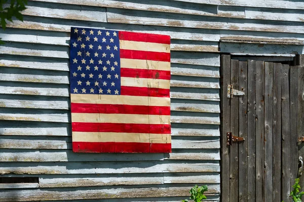 Painted American flag on side of old wooden farm building.