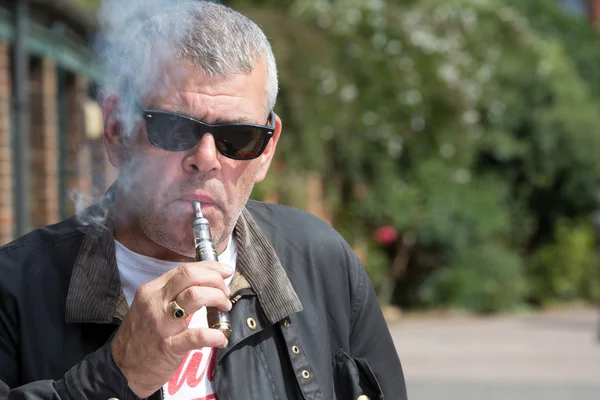 Adam bir e sigarasından şişirme güneş gözlüğü — Stok fotoğraf