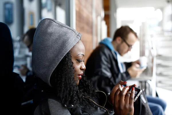 Cabelo encaracolado mulher na capa cinza usando telefone — Fotografia de Stock