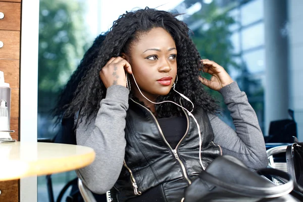 Mujer negra rizada escuchando música usando auriculares — Foto de Stock