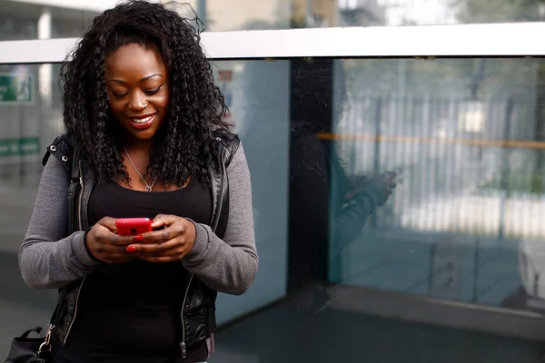 Jovem mulher africana enviando um SMS em seu celular — Fotografia de Stock