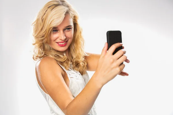 Женщина в белом платье делает селфи на мобильном телефоне — стоковое фото