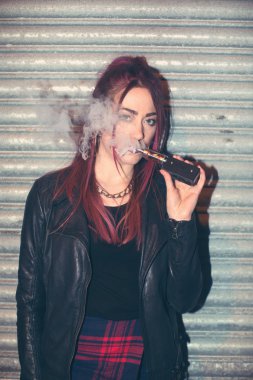 Trendy genç kadın bir e sigarasından şişirme