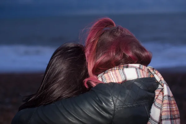 Close Up van vrouwen knuffelen op strand in de schemering Stockfoto