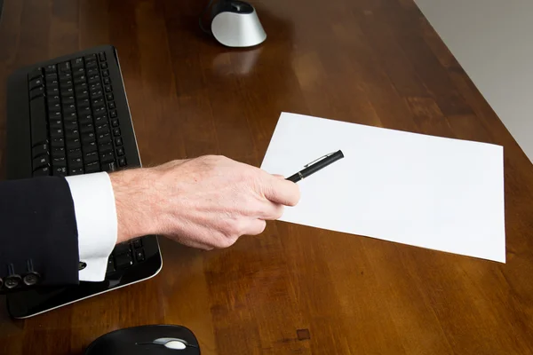 Zakenman die houdt een pen over een blanco papier blad — Stockfoto