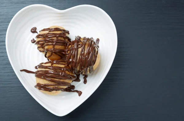 Tre pasticcini con salsa di cioccolato su un piatto Immagine Stock