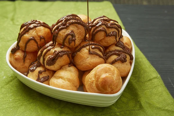 Gustosi pasticcini con sciroppo di cioccolato su piatto — Foto Stock