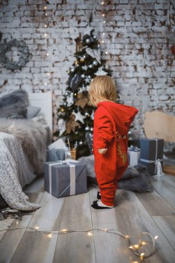 Kırmızı, sıcak kazaklı küçük bir kız Noel ağacının altında oyuncaklarla ve hediyelerle oturuyor. Mutlu bir çocukluk. Yeni yıl tatili atmosferi