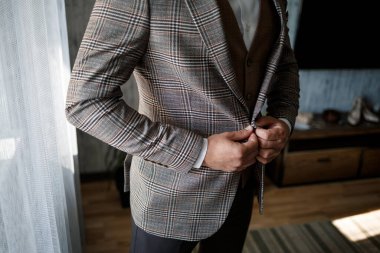 Şık damat ceketinin düğmesini ilikliyor.