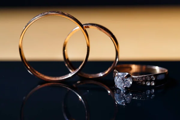 gold wedding rings for newlyweds on a wedding day on a black background with water drops. Jewelry