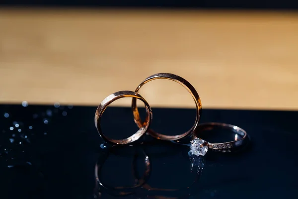 gold wedding rings for newlyweds on a wedding day on a black background with water drops. Jewelry
