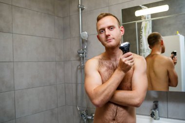 Bir adam aynanın önünde yüzünü jiletle traş eder. Deri tahrişi. Banyo prosedürü