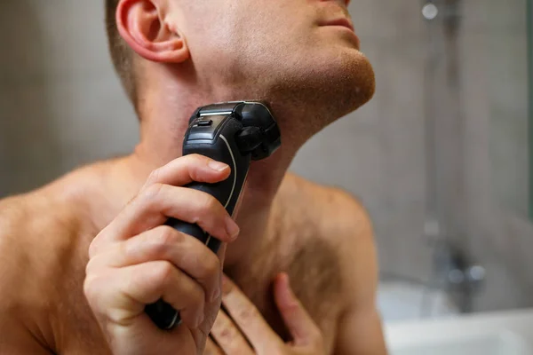 男は鏡の前で電動カミソリで顔を剃る 皮膚刺激 風呂の手順 — ストック写真