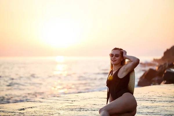 美丽的女士穿着黑色泳衣在海滨 笑容满面 金色夕阳 — 图库照片