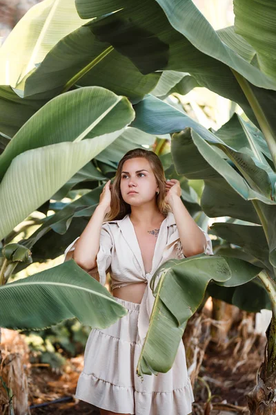 Beautiful woman in the jungle. A resort or hotel with tropical trees and plants. Woman with near banana leaf. Girl on vacation in the rainforest