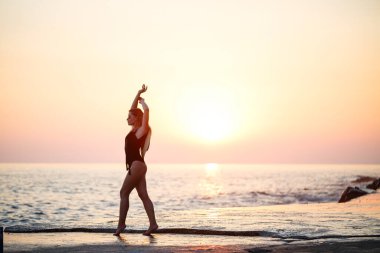 Deniz kıyısında siyah mayolu güzel bir bayan omuzlarında hasır bir şapkayla gülümseyen bir yüz. Altın günbatımı ışığı