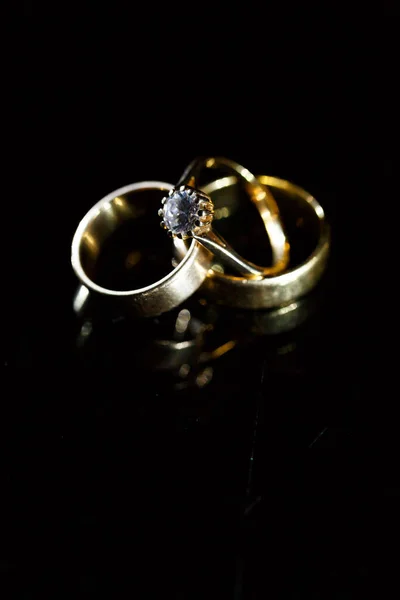 ブラックガラス上の金の結婚指輪 — ストック写真