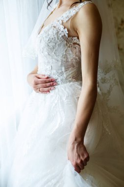 Gelin elinde güzel bir gelinlik tutuyor.