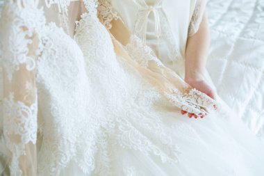 Gelin elinde güzel bir gelinlik tutuyor.