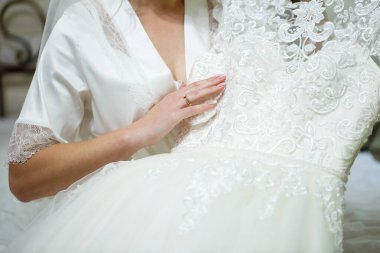 Gelin elinde güzel bir gelinlik tutuyor.