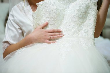 Gelin elinde güzel bir gelinlik tutuyor.