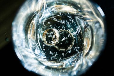 Sonbahar arkaplanının önünde nişan takıları olan şampanya kadehleri.