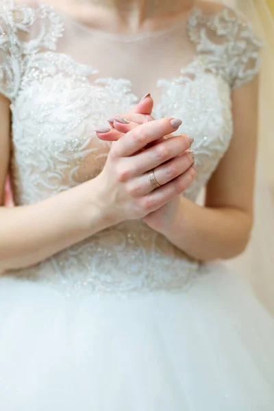 Las novias manos dobladas en un vestido de novia blanco — Foto de Stock