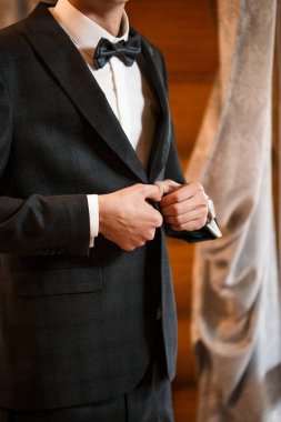 Şık damat ceketinin düğmesini ilikliyor.