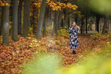 Sonbahar ormanında elbise giymiş bir kız.
