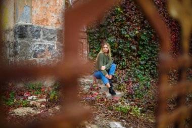 Kazak ve kot giyen güzel bir kızın yürüyüşü.