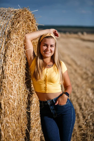 野原の若い美少女が軒先に立っている 村での休暇 若いです女性で黄色の上とジーンズ — ストック写真