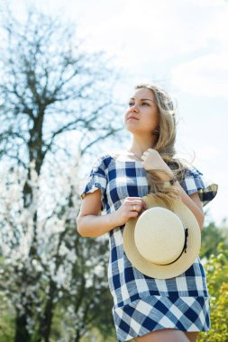 Ağaçların çiçek açtığı bahar ormanında yürüyen elbiseli güzel bir kız.