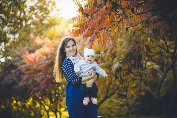 Krásná Žena Šatech Hraje Dítětem Náručí Stojí Podzimní Přírodě Padajícím — Stock fotografie