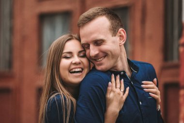 Mutlu çift sarılıyor ve gülümsüyor. Yüzlerinde gülümseme olan bir erkek ve bir kızın portresi..